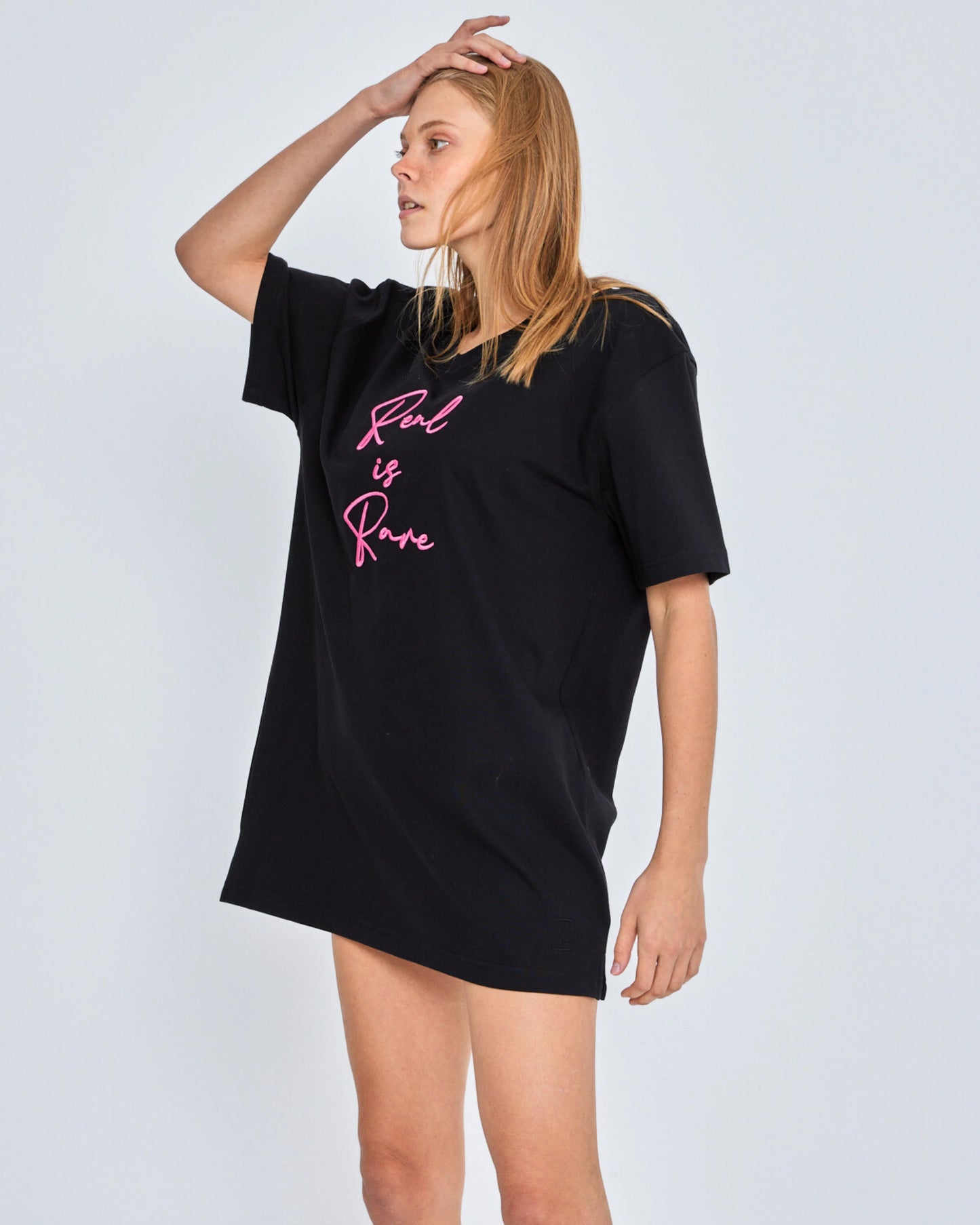 Woman wearing a black t-shirt with pink text on a white background