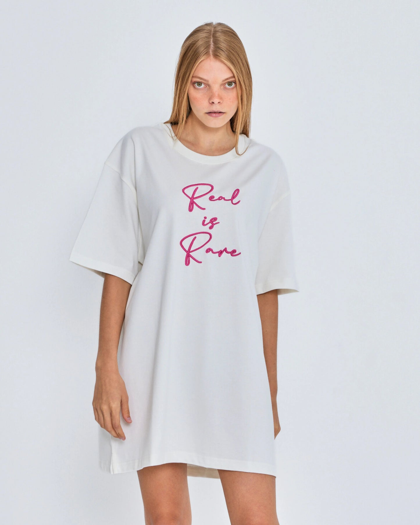 White oversized t-shirt with 'Real is Rare' text on a plain background