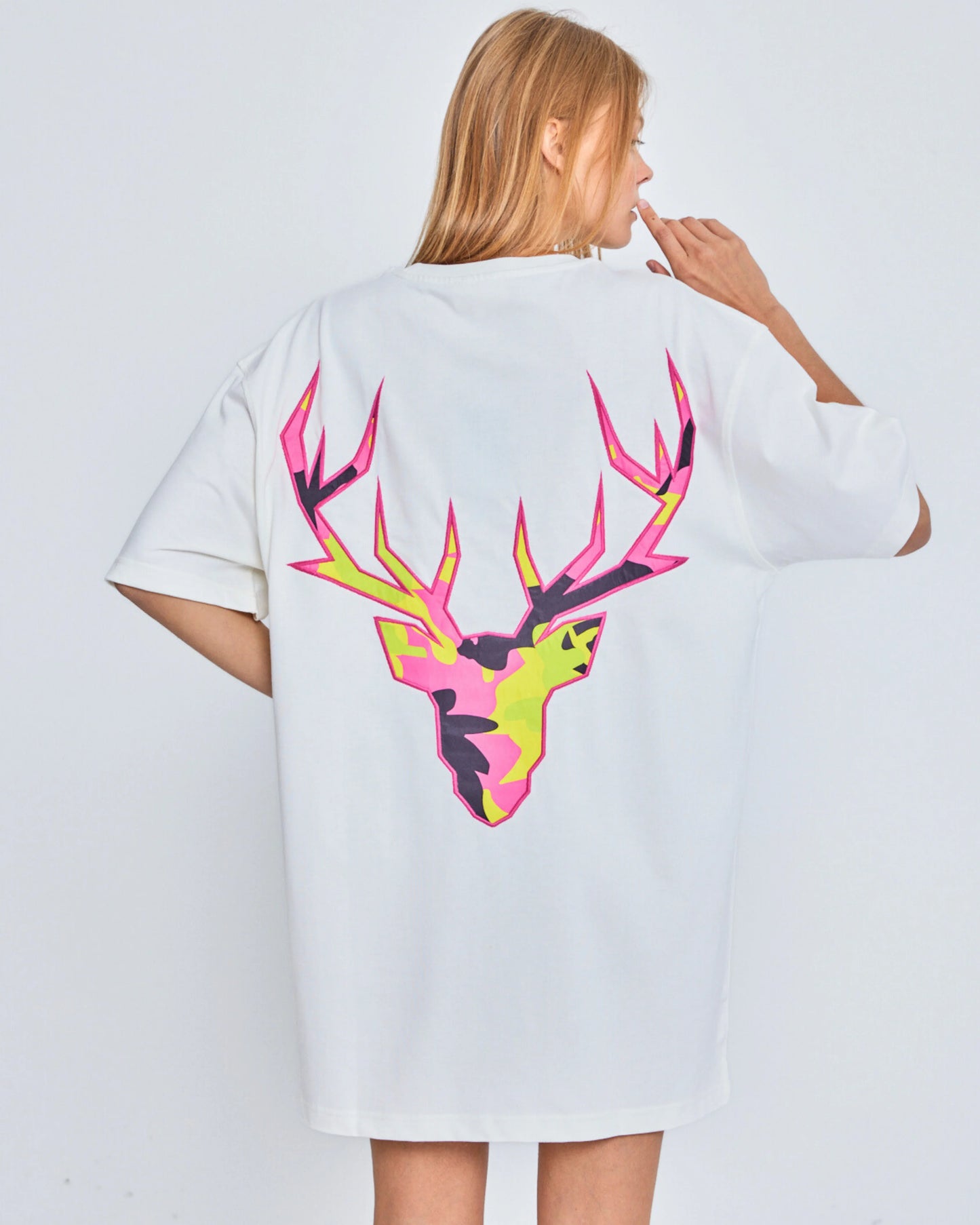 Person wearing a white t-shirt with a colorful deer design on the back against a plain background