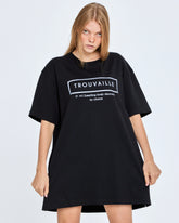 Person wearing a black oversized t-shirt with 'TROUVAILLE' text on a plain background