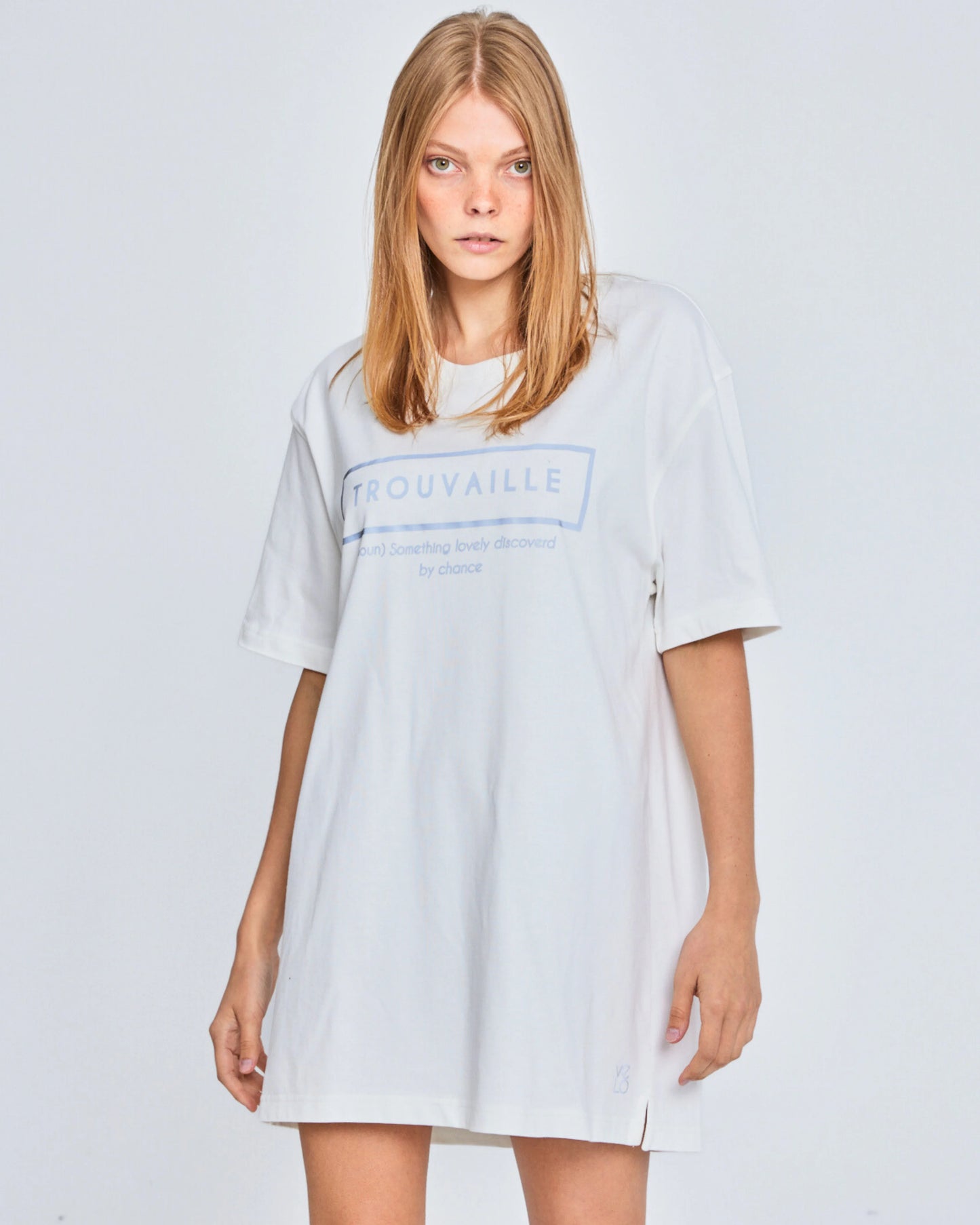Woman wearing a light gray t-shirt dress with 'Trouvaille' logo on a white background