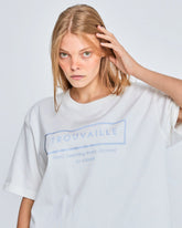 Person wearing a white t-shirt with 'Trouvaille' branding on a plain background