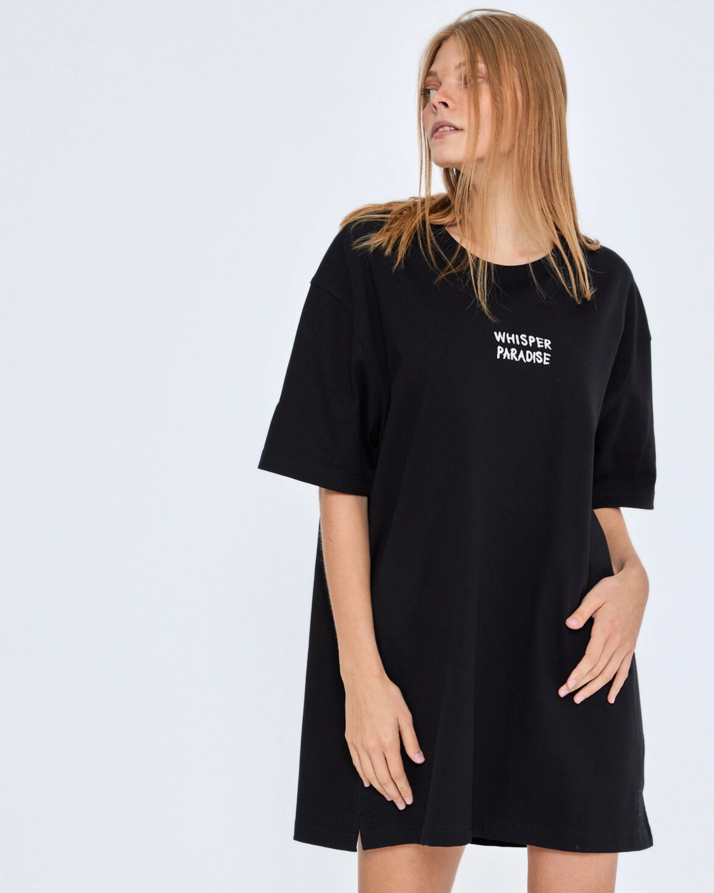 Person wearing a black t-shirt with 'Whisper Paradise' text on a white background