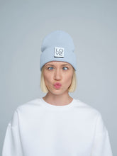 A person wearing a baby blue beanie with a 'Love' text design patch on the front.
