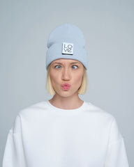 A person wearing a baby blue beanie with a 'Love' text design patch on the front.
