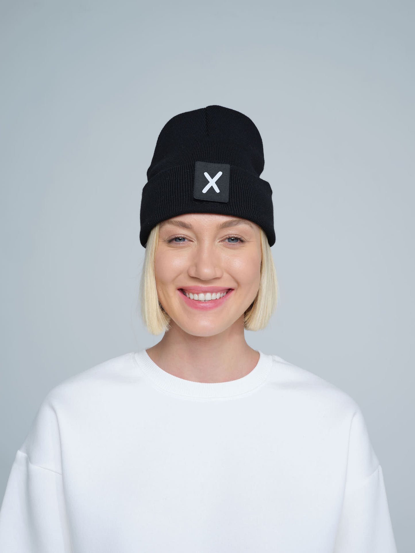 women wearing black beanie with X letter patch on it with smiley face