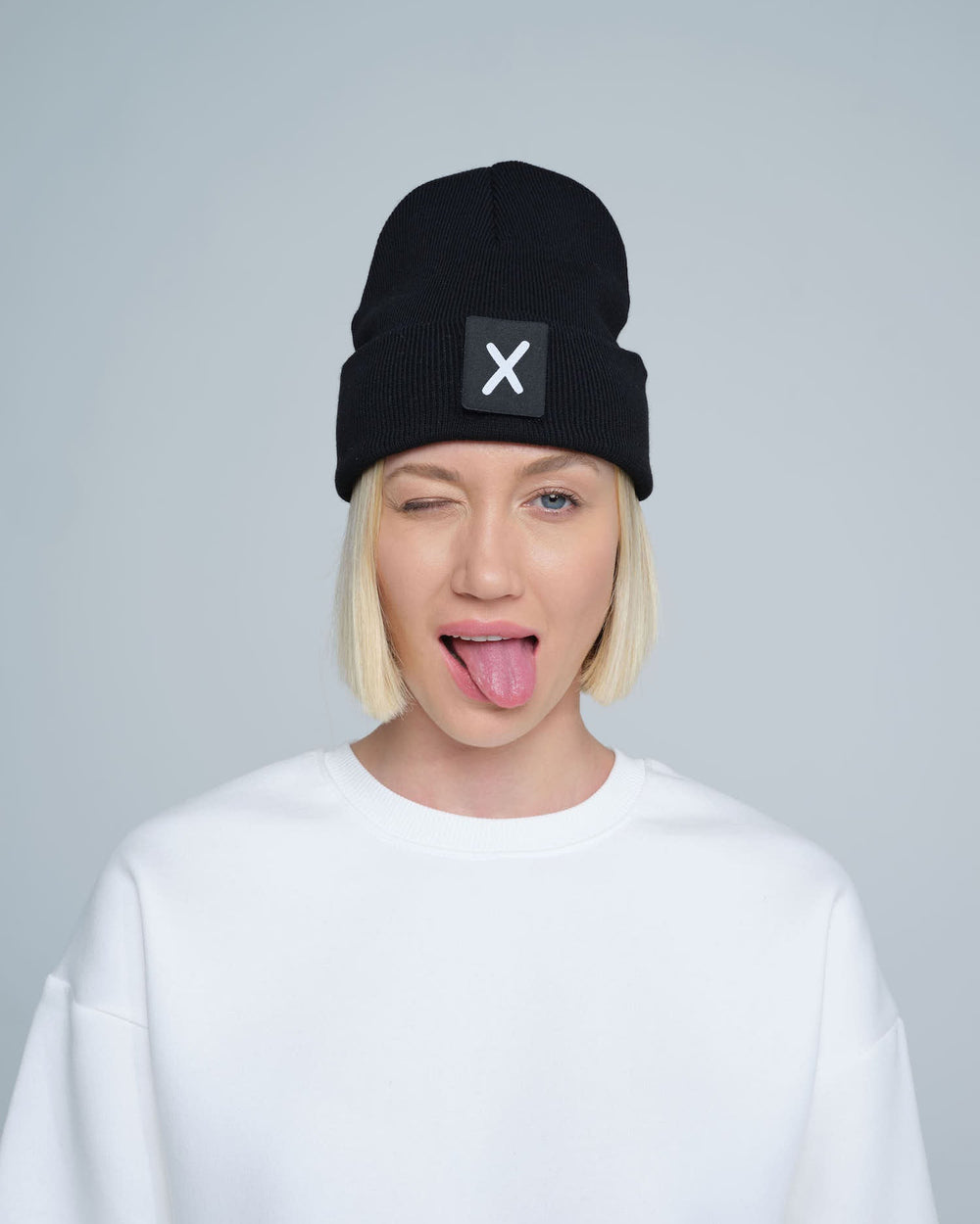 women wearing black beanie with X letter patch on it