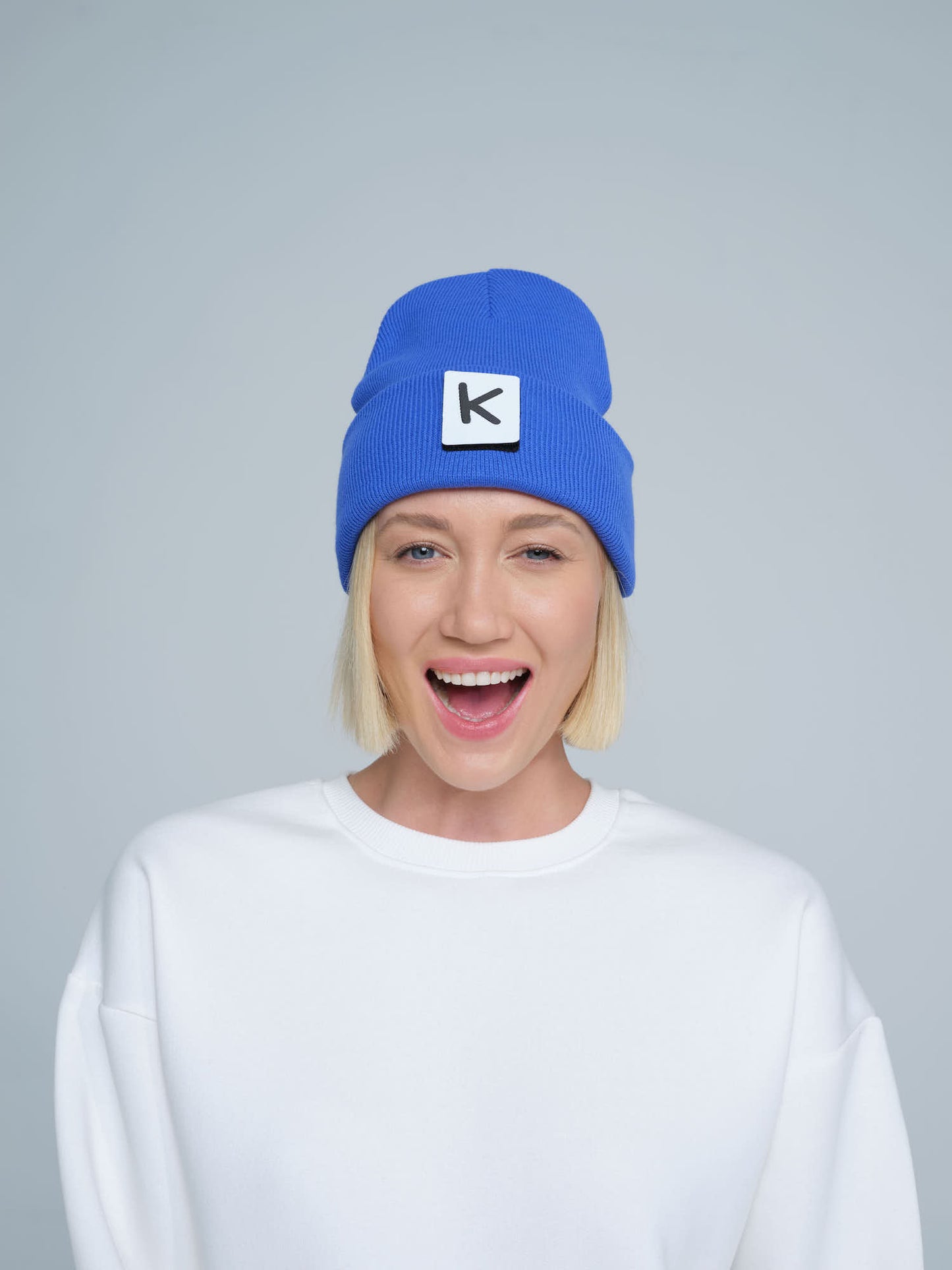 female model wearing blue beanie with K letter patch on it