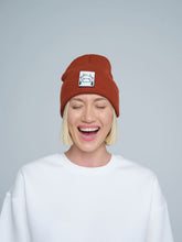 woman wearing burnt orange beanie with a cow patch on the front