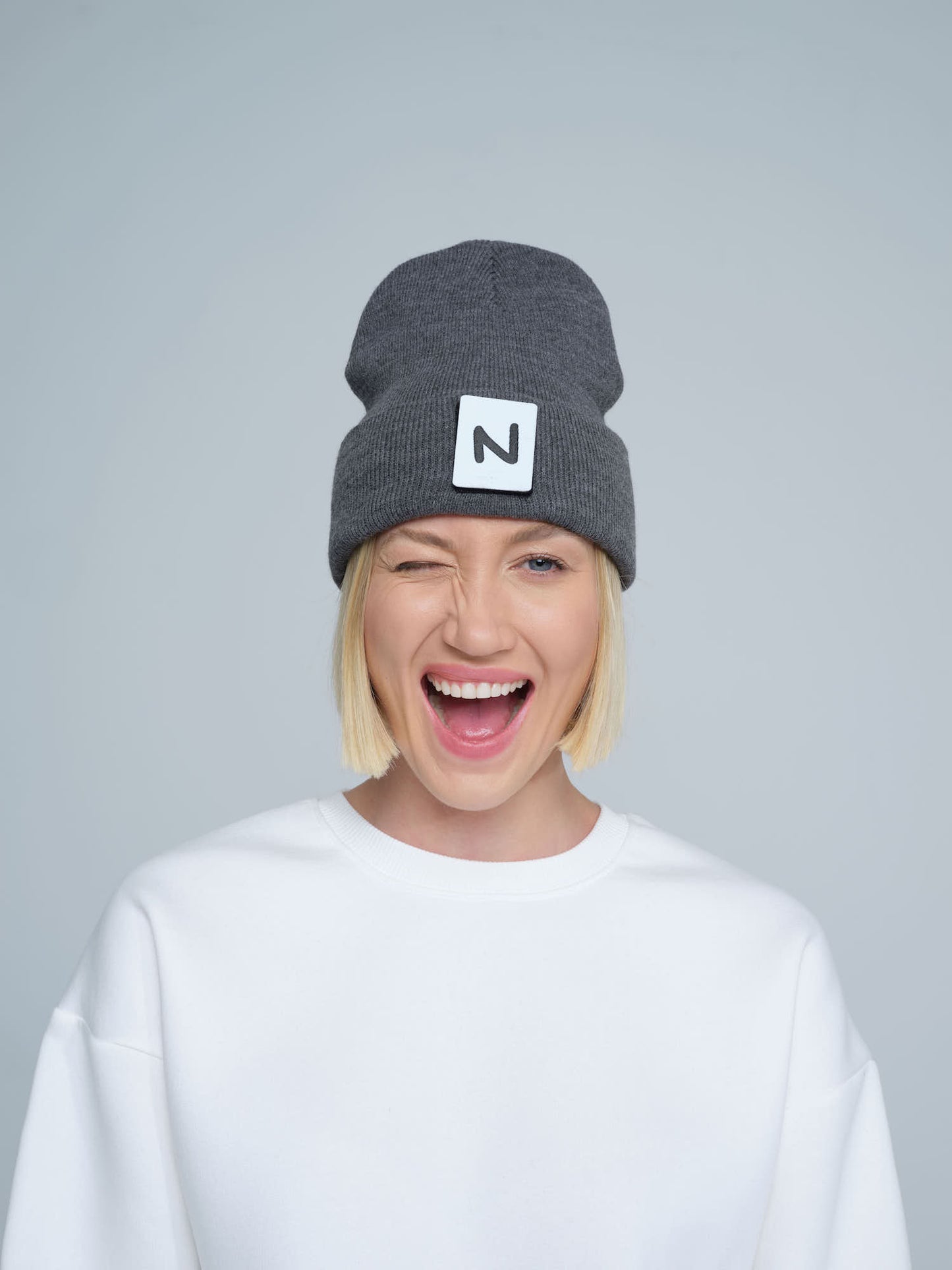 women model wearing dark grey patch ready beanie with 'N' letter patch on the front