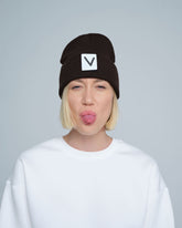 A person wearing an espresso beanie hat with a 'V' letter design on the cuff, and a white t-shirt.