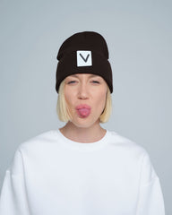 A person wearing an espresso beanie hat with a 'V' letter design on the cuff, and a white t-shirt.