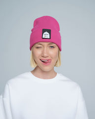 A person wearing a pink beanie with a 'duck' animal design on the fold, part of a white crew neck sweater.