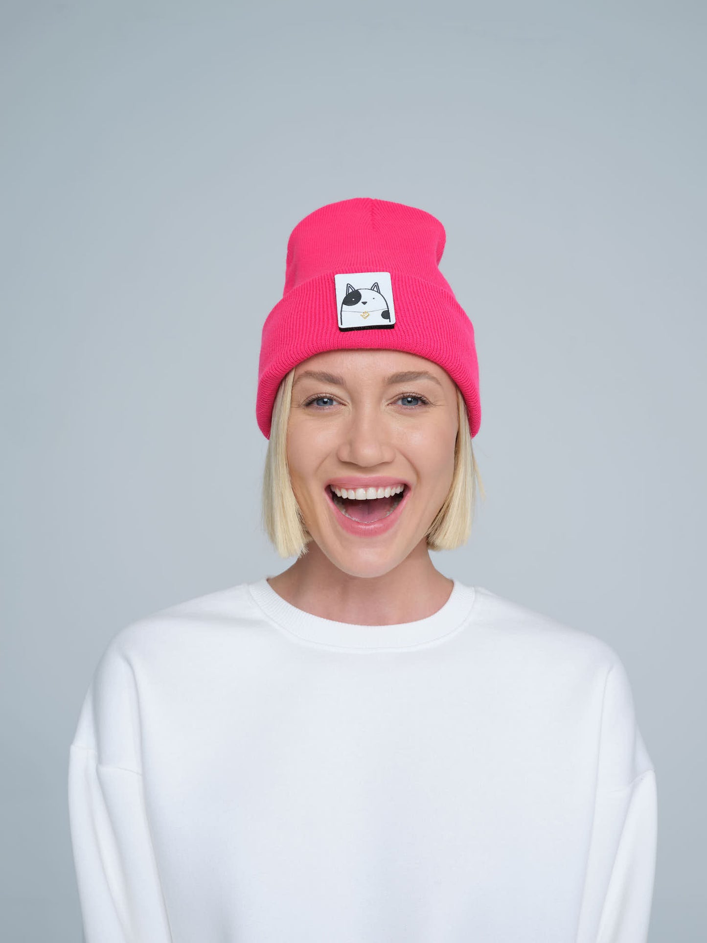 women wearing neon pink beanie with a cat design patch on the front