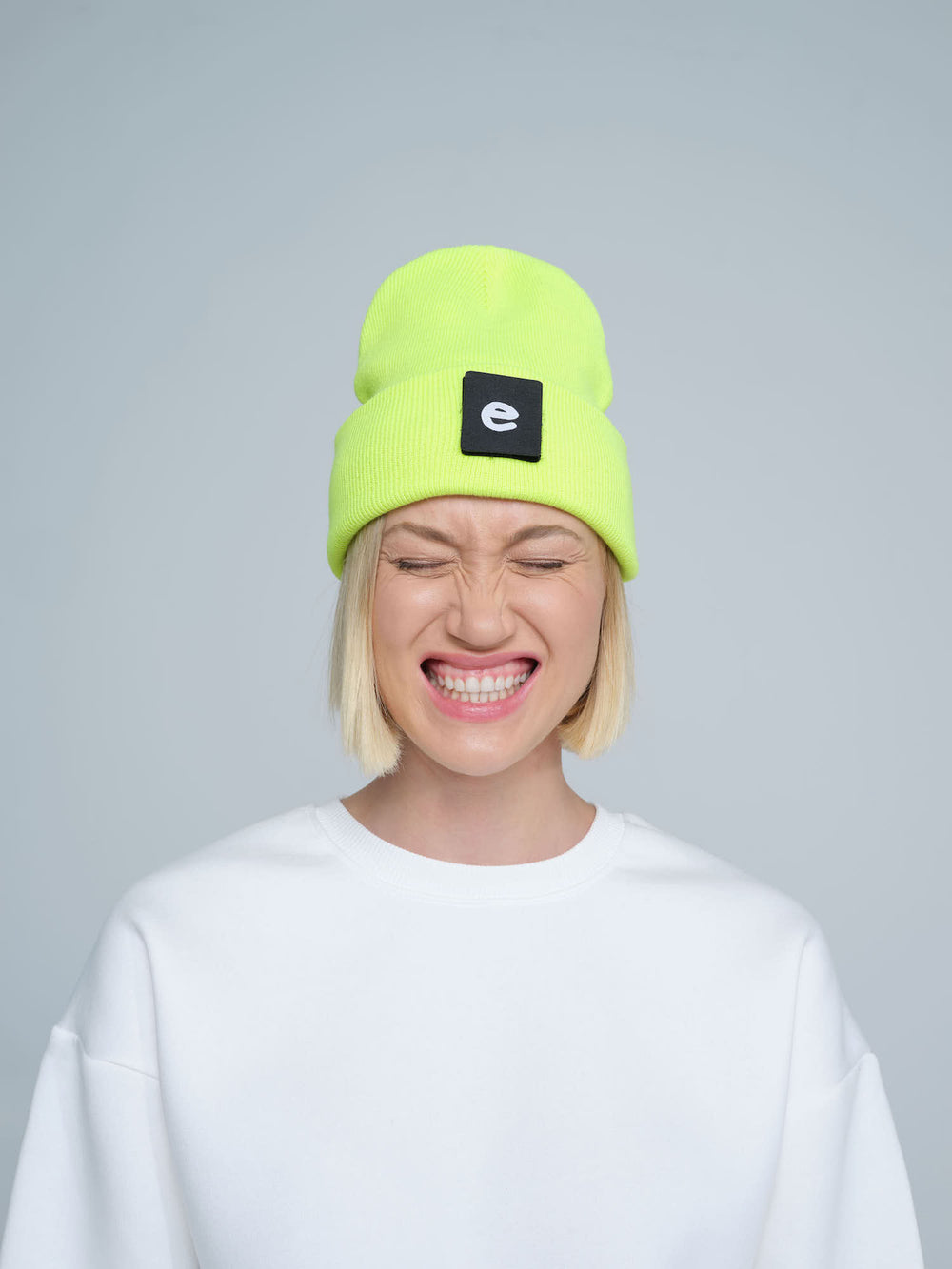 women wearing neon yellow beanie with a 'e' letter patch on it