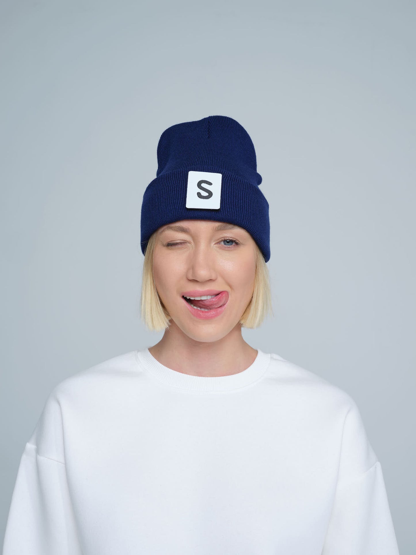 women wearing night blue beanie with 'S' letter patch on it