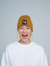 female model wearing peru colour patch ready beanie with 'u' letter on it and smiling