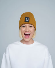 female model wearing peru colour patch ready beanie with 'u' letter on it and smiling