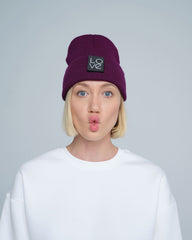 A person wearing a purple beanie hat with a 'Love' patch on the front.