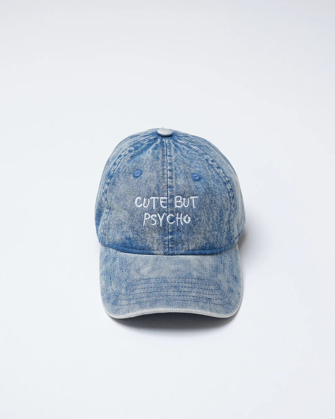Blue denim cap with 'Cute But Psycho' text on a white background