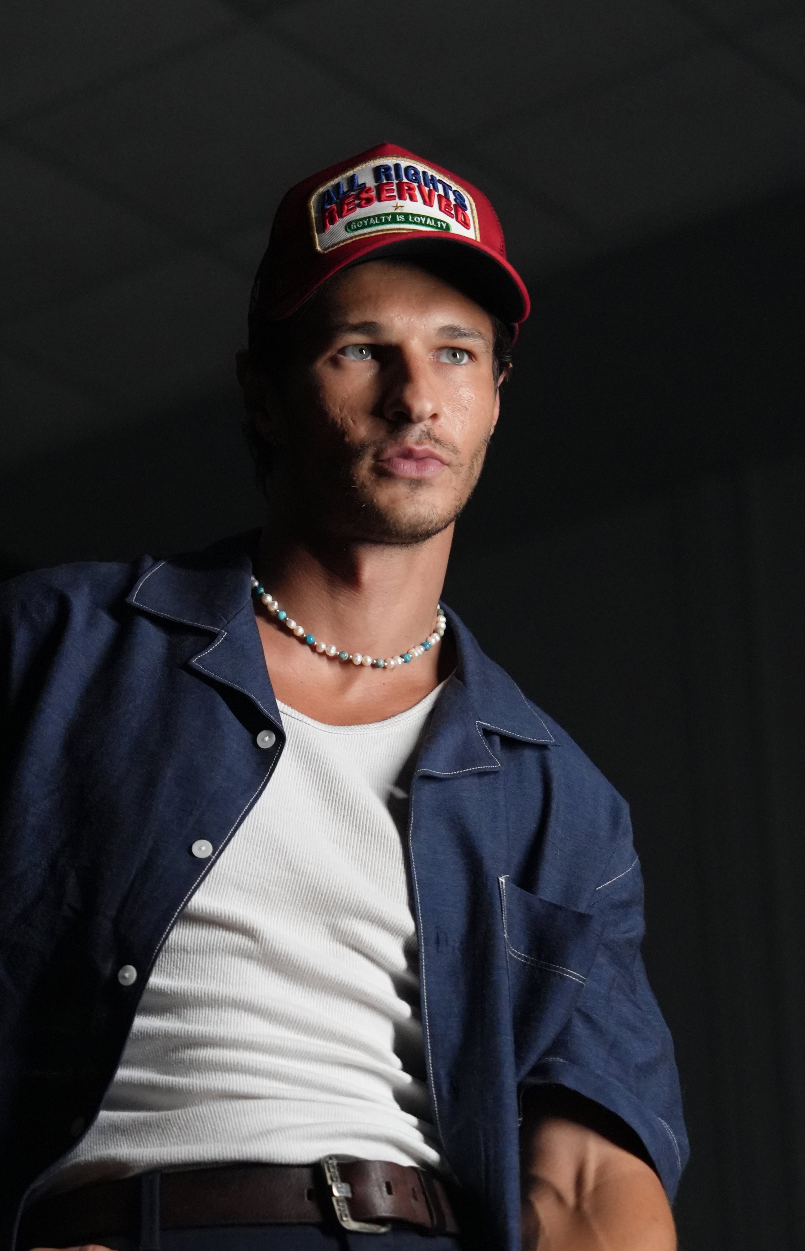 Man wearing All Rights Reserved Red Trucker Hat and casual outfit against a dark background