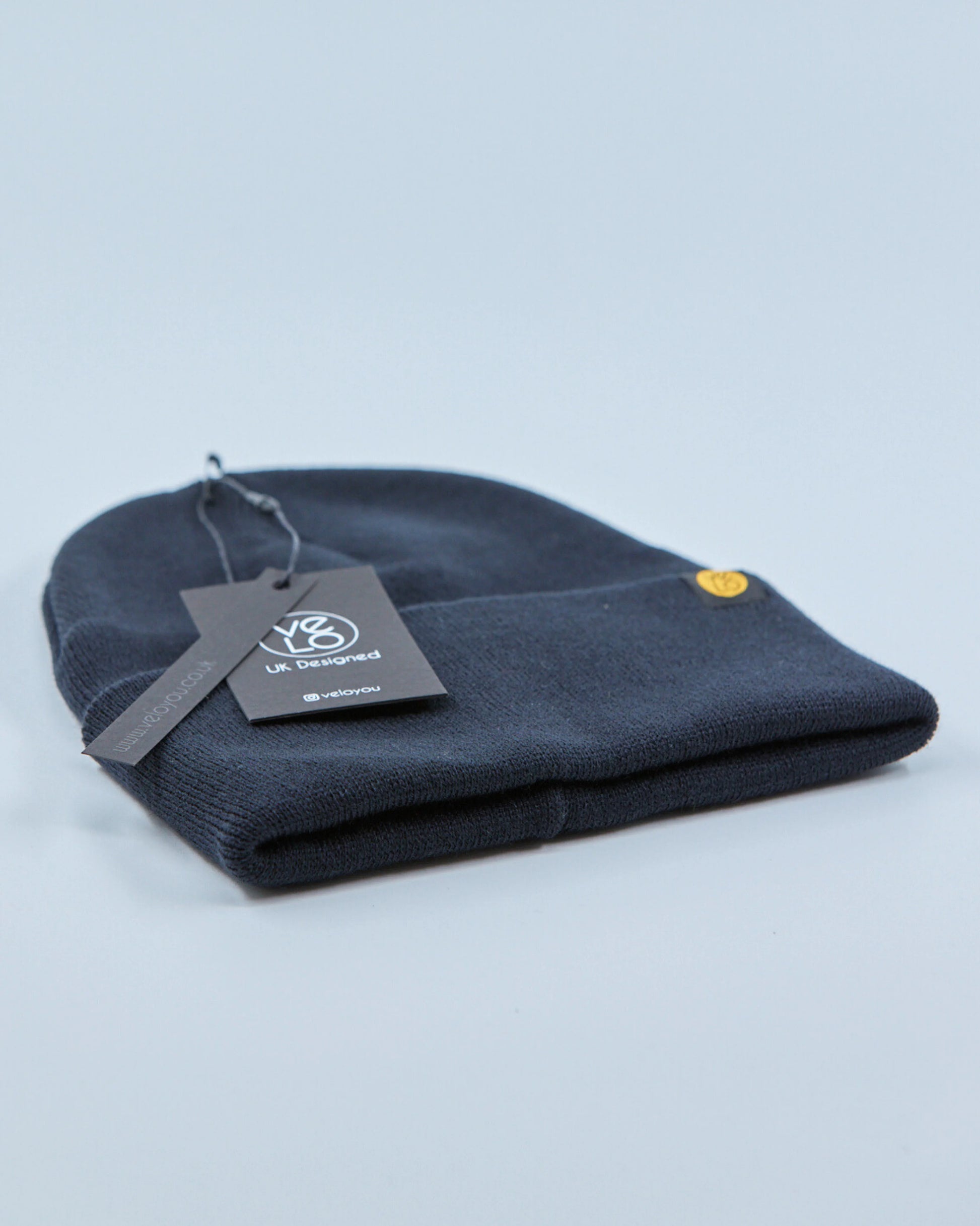 Charcoal navy blue beanie with a tag on a light gray background
