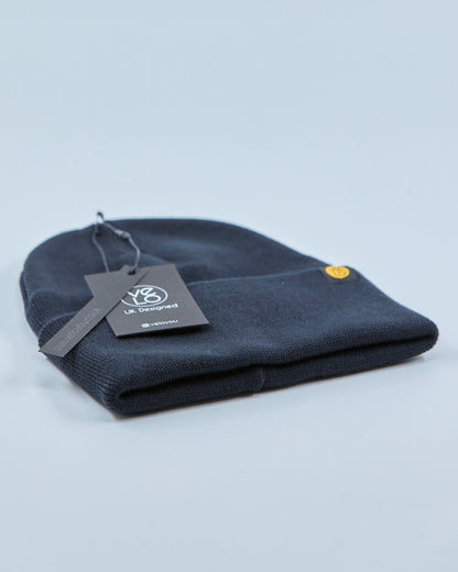Charcoal navy blue beanie with a tag on a light gray background