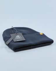 Charcoal navy blue beanie with a tag on a light gray background