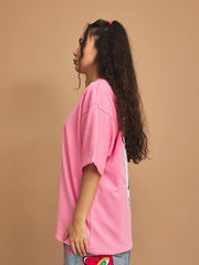 Person wearing a pink oversized t-shirt with a white stripe on a brown background