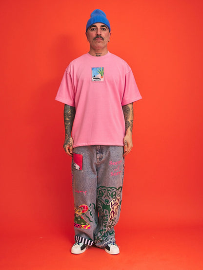 Person wearing a pink t-shirt and gray pants with colorful designs against an orange background