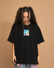 Person wearing a black t-shirt with a small graphic on a brown background