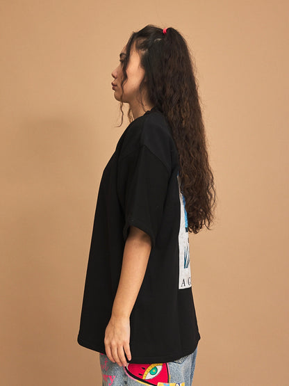 Person wearing a black oversized t-shirt against a brown background