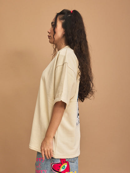 Woman wearing a beige oversized t-shirt against a brown background