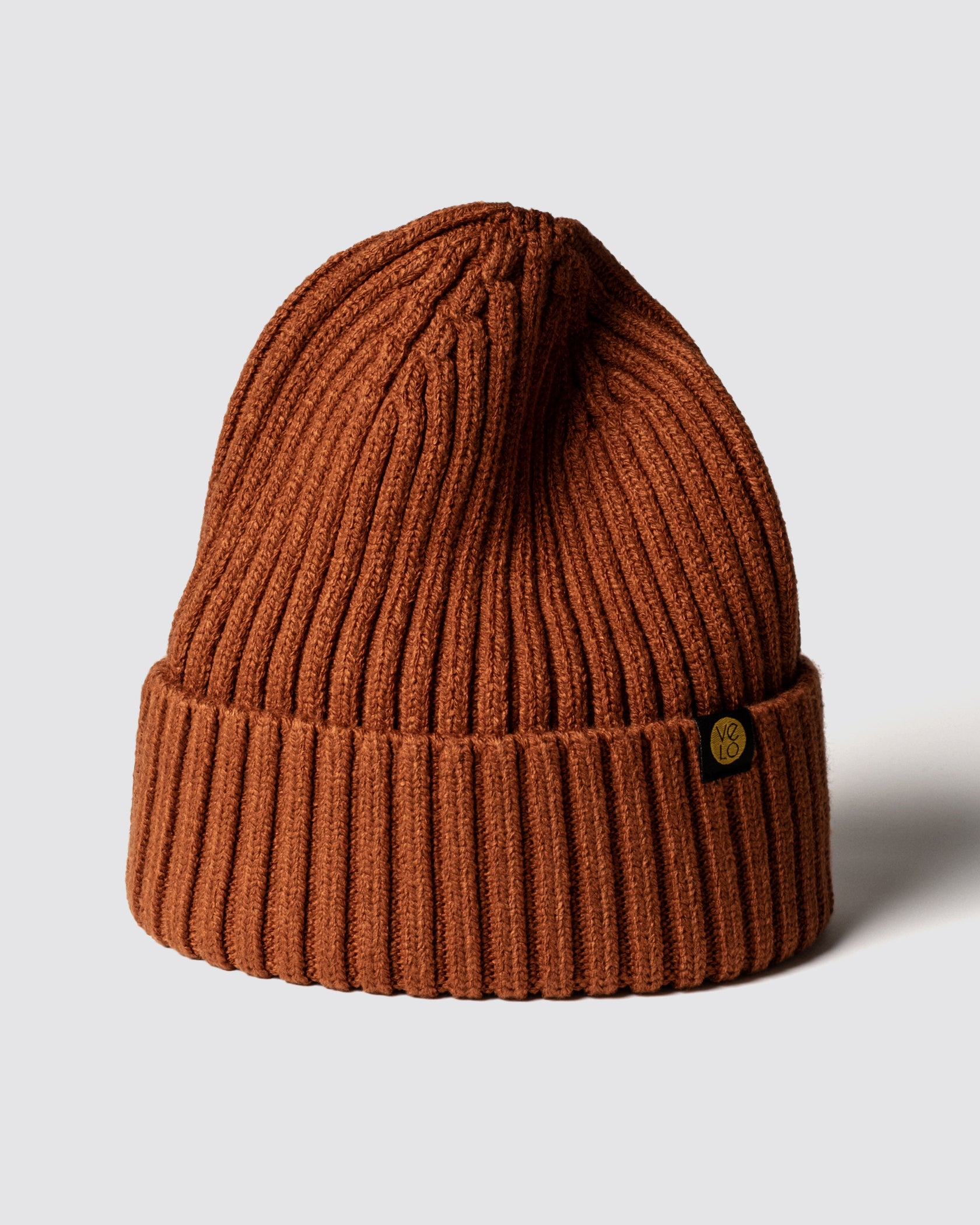 Cinnamon knit beanie with a logo on a light gray background