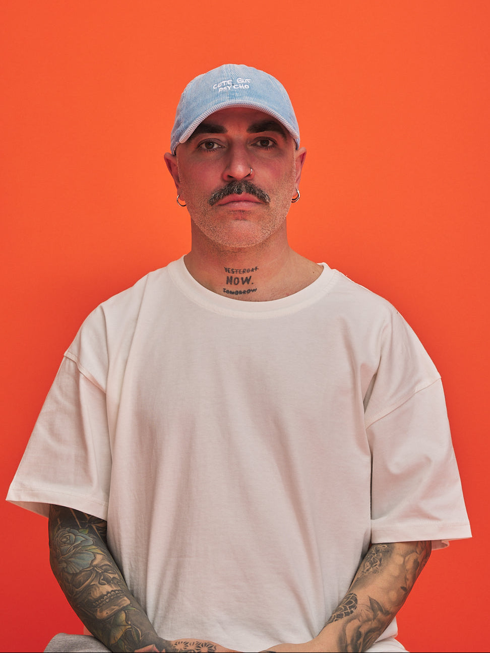 Man wearing a light blue cap and white t-shirt against an orange background