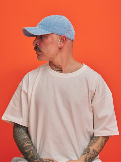 Person wearing a light blue cap and white t-shirt against an orange background