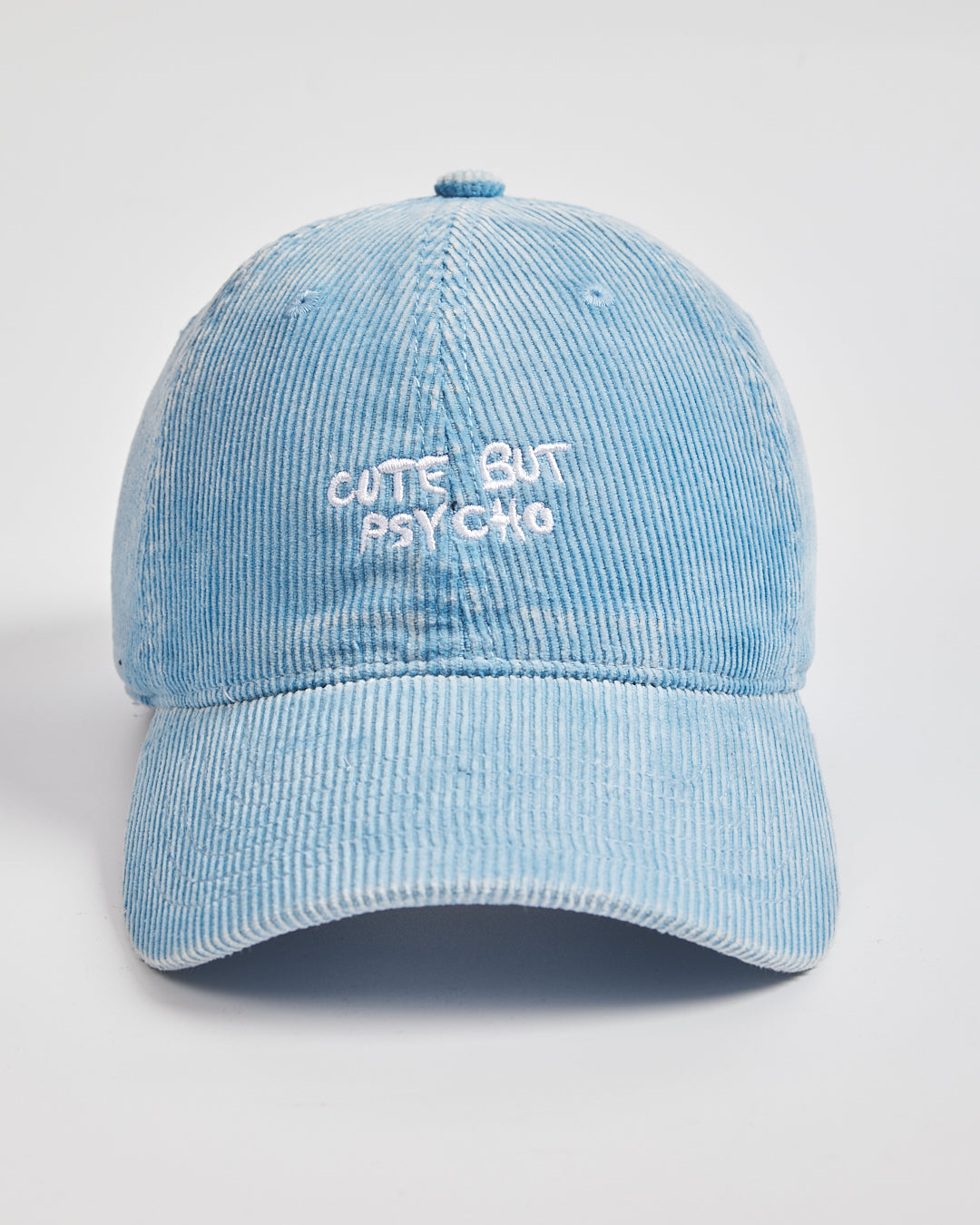 Light blue corduroy cap with 'Cute But Psycho' text on a light gray background