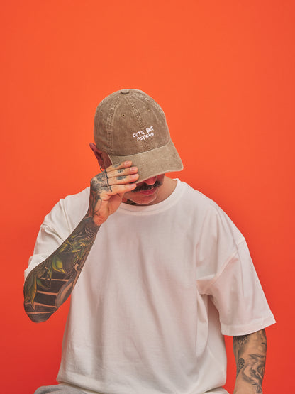 Person wearing a beige cap and white t-shirt against an orange background