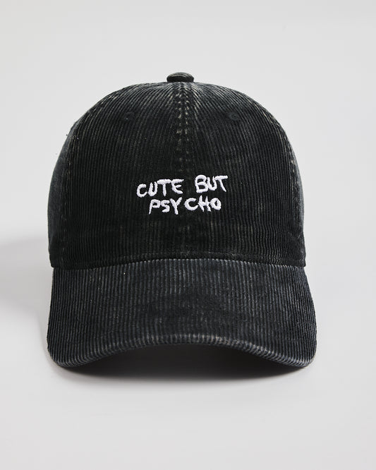 Black corduroy cap with 'Cute But Psycho' text on a light gray background