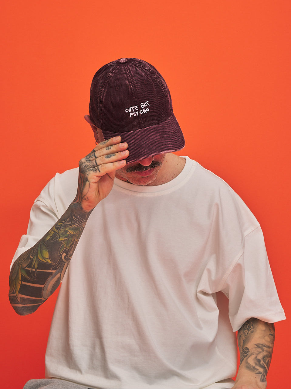 Person wearing a cap with 'Cute But Psycho' text on an orange background
