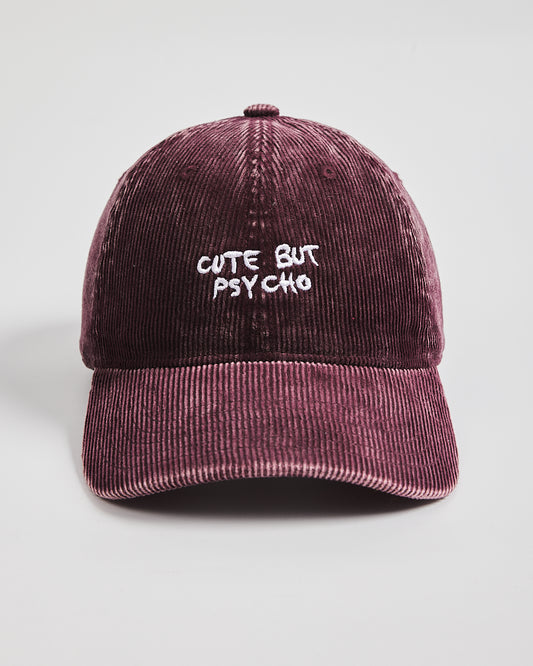 Maroon corduroy cap with 'Cute But Psycho' text on a light gray background