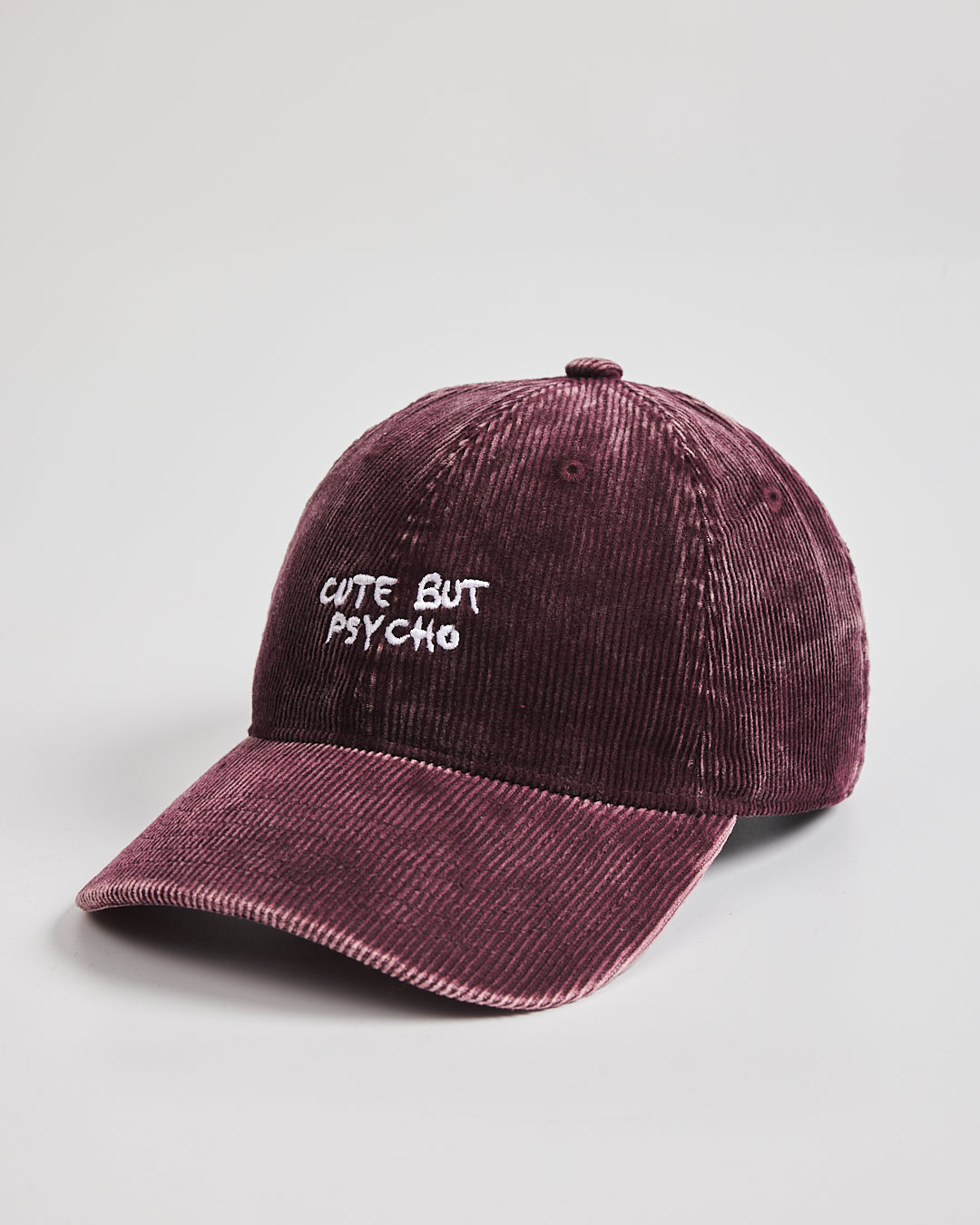 Corduroy cap with 'Cute But Psycho' text on a light gray background