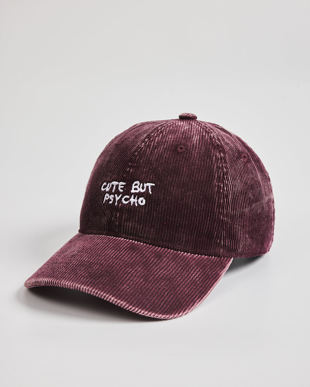 Corduroy cap with 'Cute But Psycho' text on a light gray background