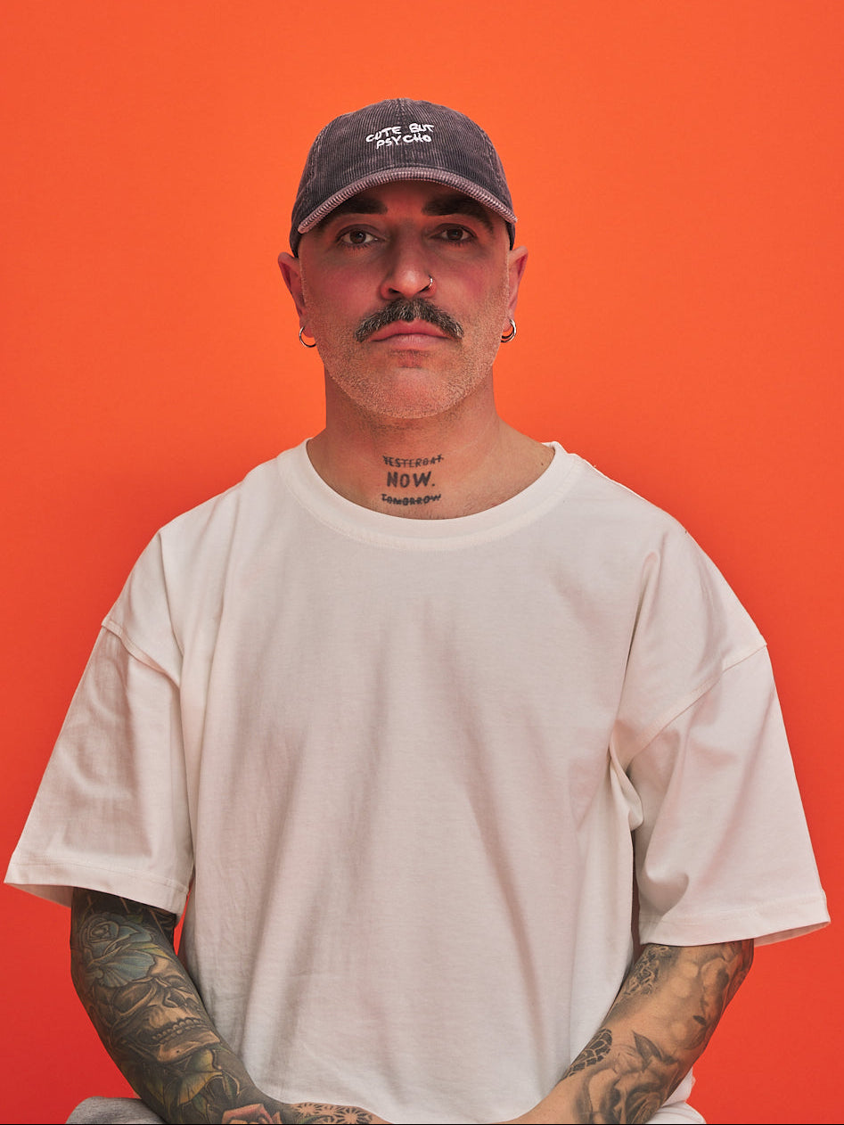Front look of man wearing a cap and white t-shirt against an orange background