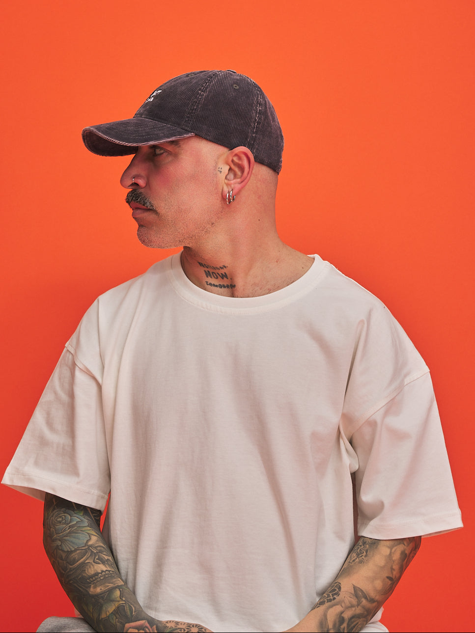 Man wearing a cap and white t-shirt against an orange background