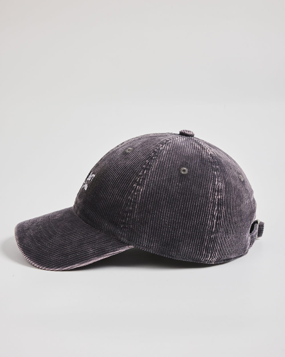 Side look of charcoal grey corduroy cap on a light gray background