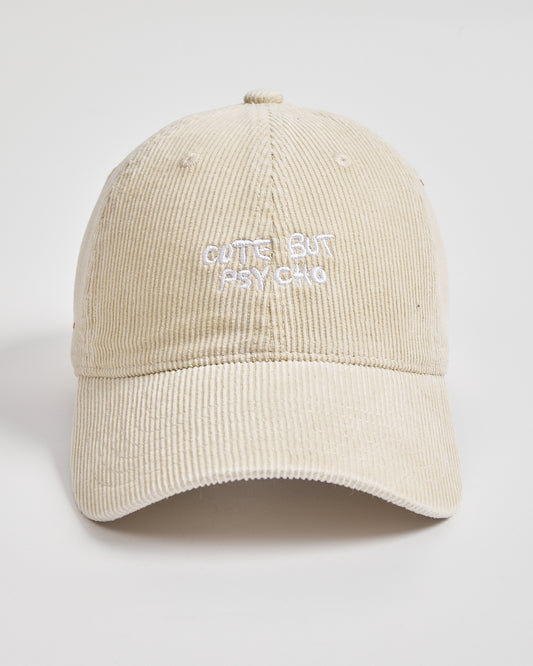 Cream corduroy cap with 'Cute But Psycho' text on a light gray background