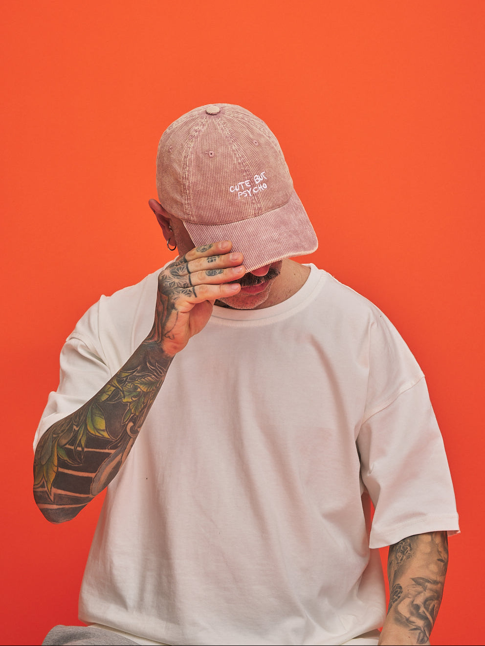Person wearing a pink cap and white t-shirt against an orange background