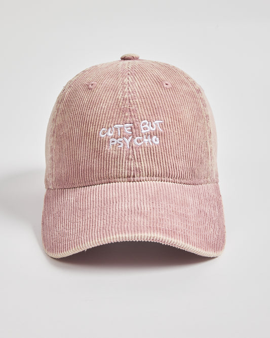 Pink corduroy cap with 'Cute But Psycho' text on a light gray background