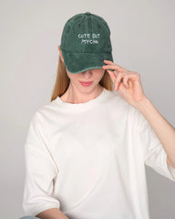 Front look of female model holding cute but psycho green washed cap